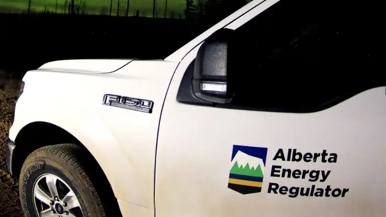White Ford F-150 pickup truck with Alberta Energy Regulator logo on the door photographed at night outdoors