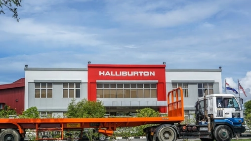 Halliburton corporate facility with bold red signage and national flags, an orange truck in the foreground
